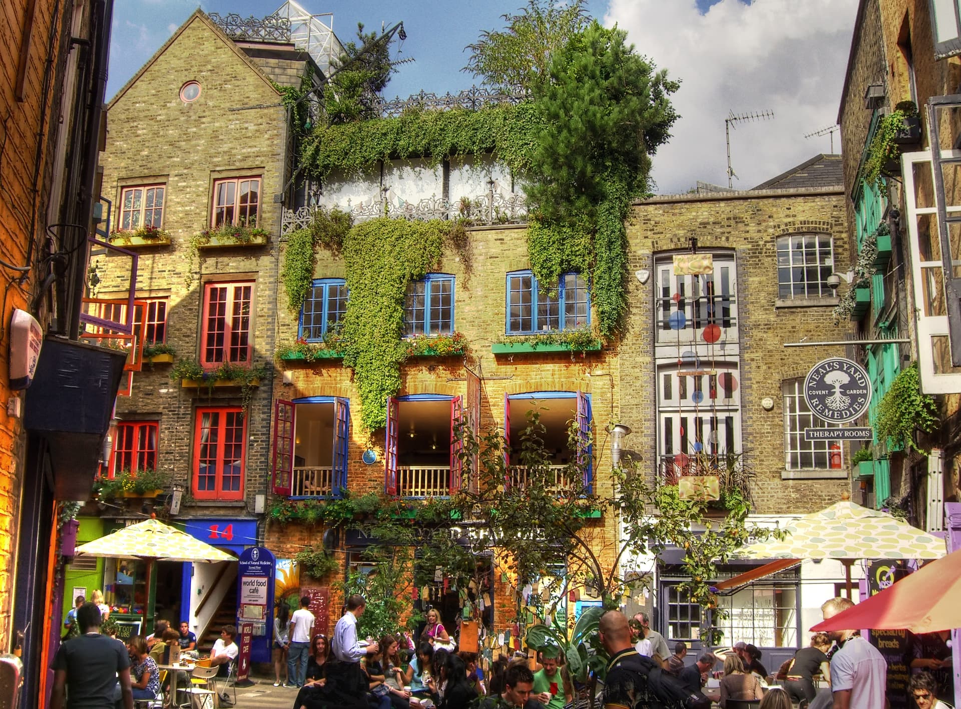 Colourful ivy-covered brick buildings and busy outdoor café seating in Neal's Yard, Covent Garden