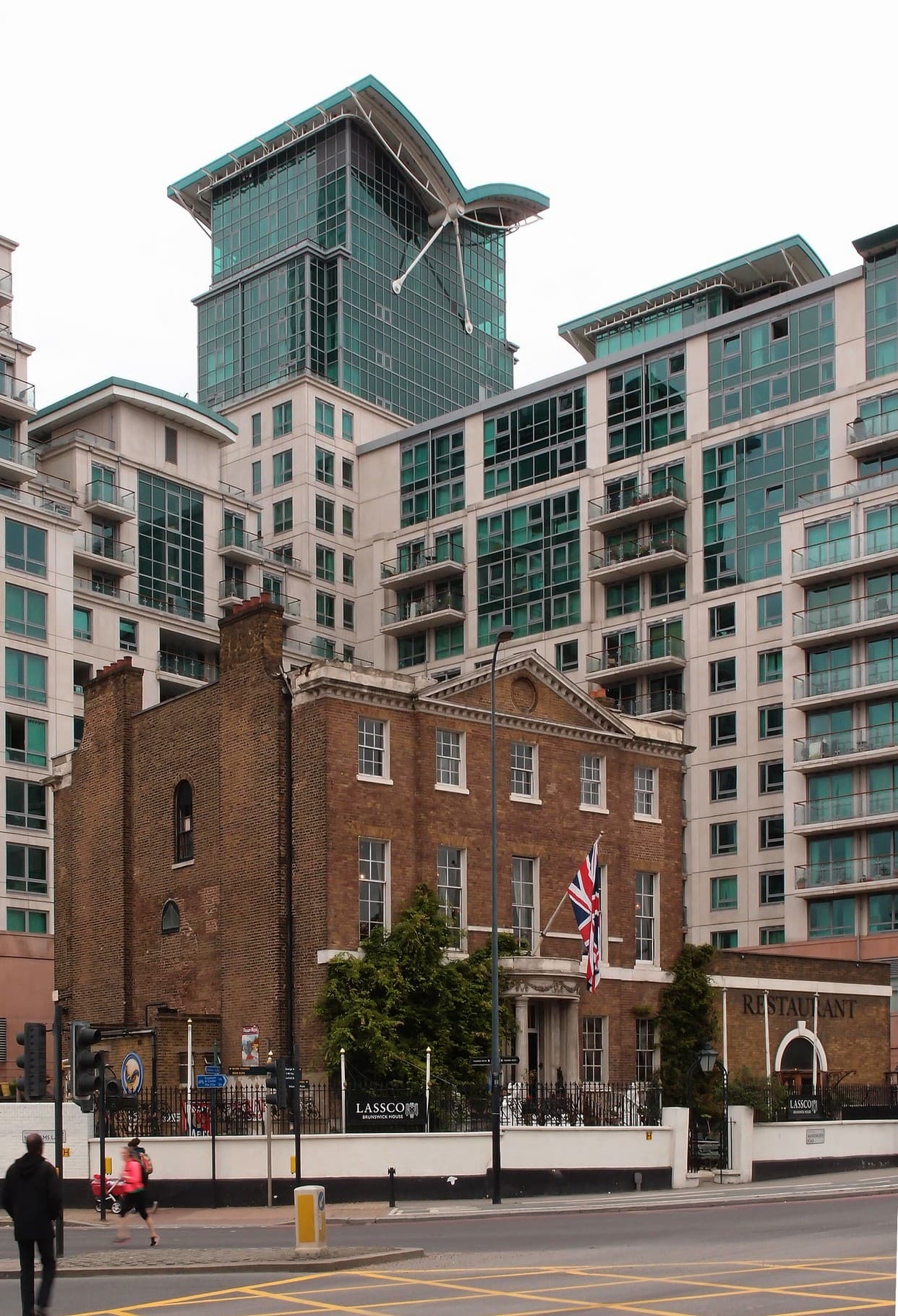 Georgian brick house with a Union flag, dwarfed by modern glass residential towers in Vauxhall