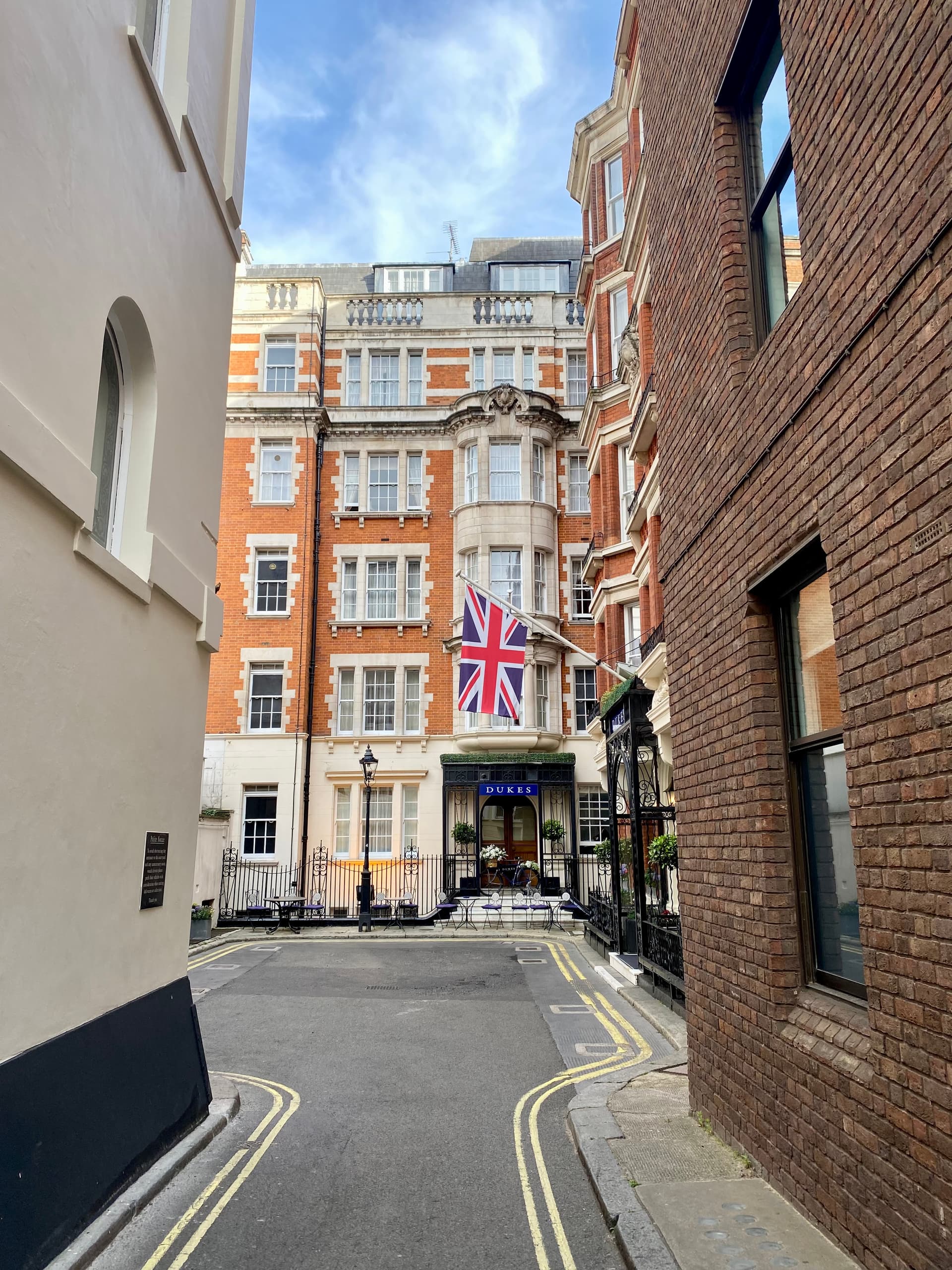 Red-brick Edwardian hotel entrance with Union flag at the end of a quiet St James's lane